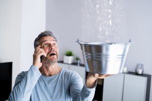 A man calling an emergency plumbing service because of a ceiling pipe leak.
