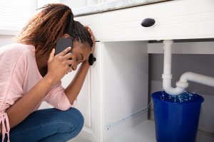 woman calling a plumber to repair a leaking pipe.